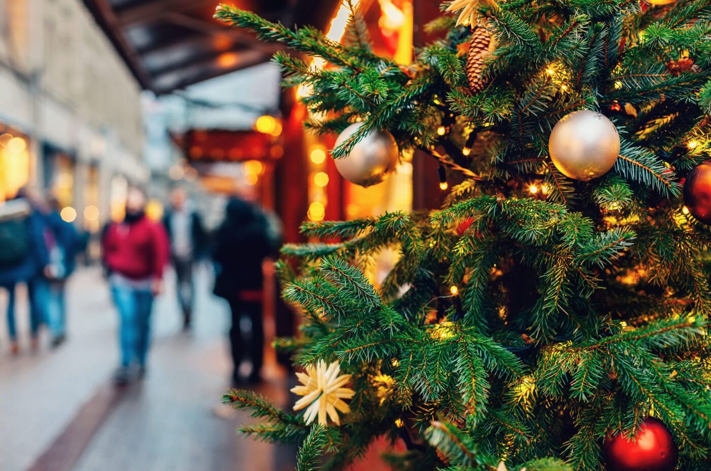 A decorated Christmas tree in the foreground of a traditional Christmas market in Newcastle in the evening.